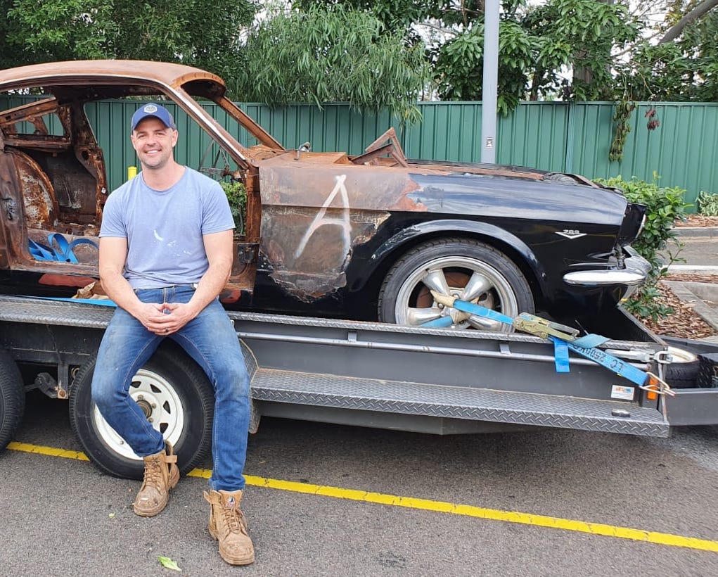 Simon Leven Owner of Leven Restorations sitting on a 1965 Mustang